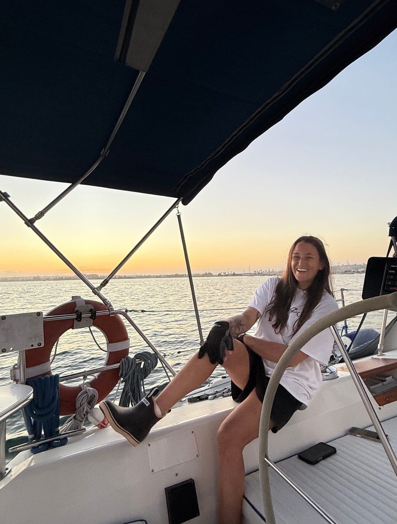Captain Liz laughing at the helm of the Mojave during a sunset sail on San Diego Bay