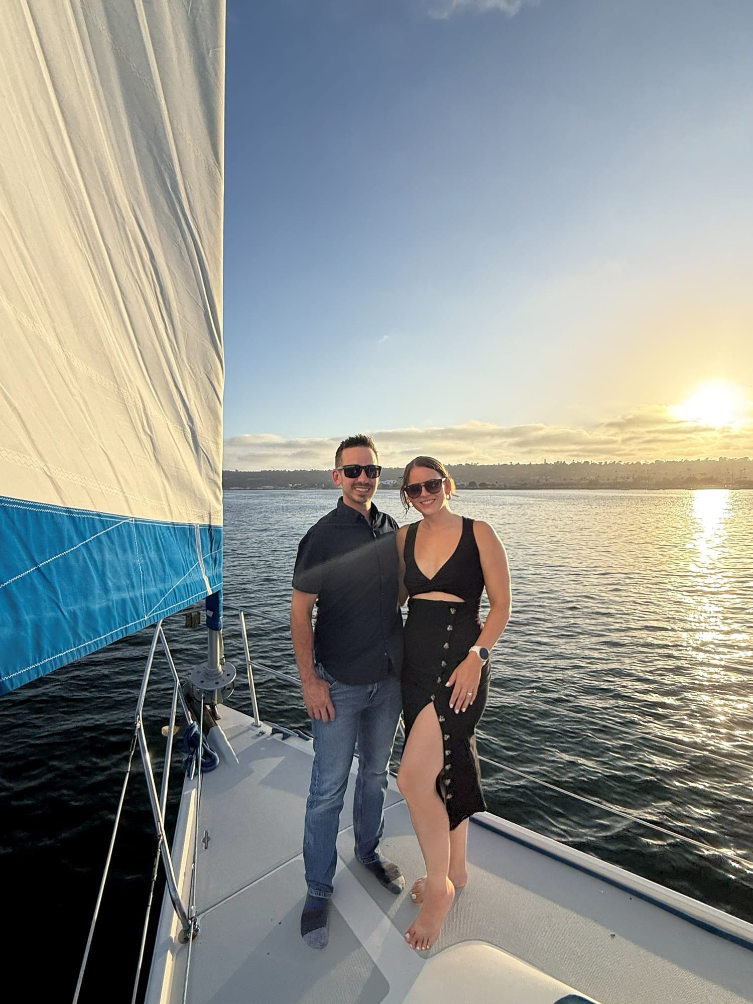 A couple on the bow of the Mojave under sail as the sun goes down over San Diego Bay