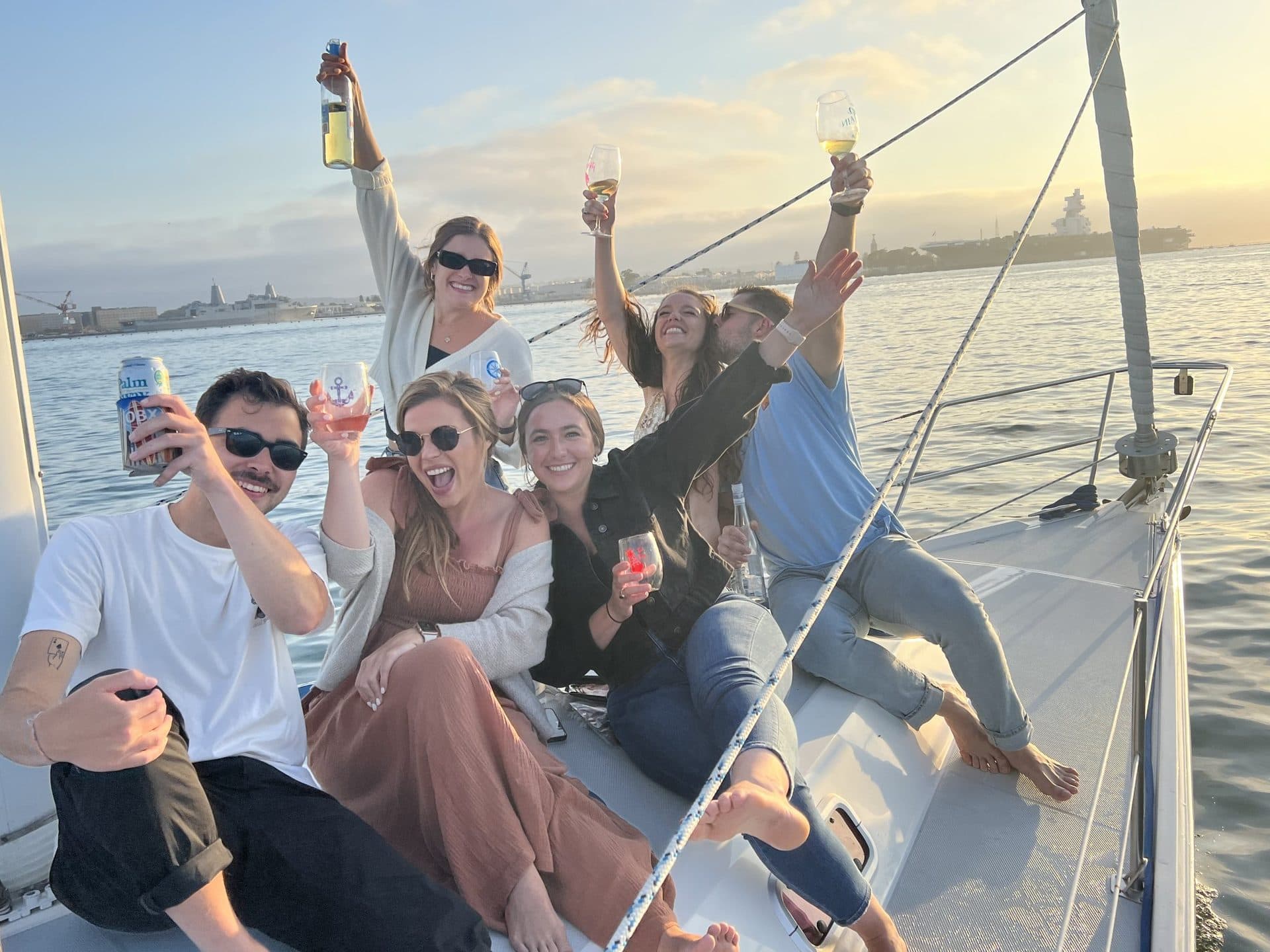 Friends toasting champagne at sunset on a Sterling Sails charter on San Diego Bay