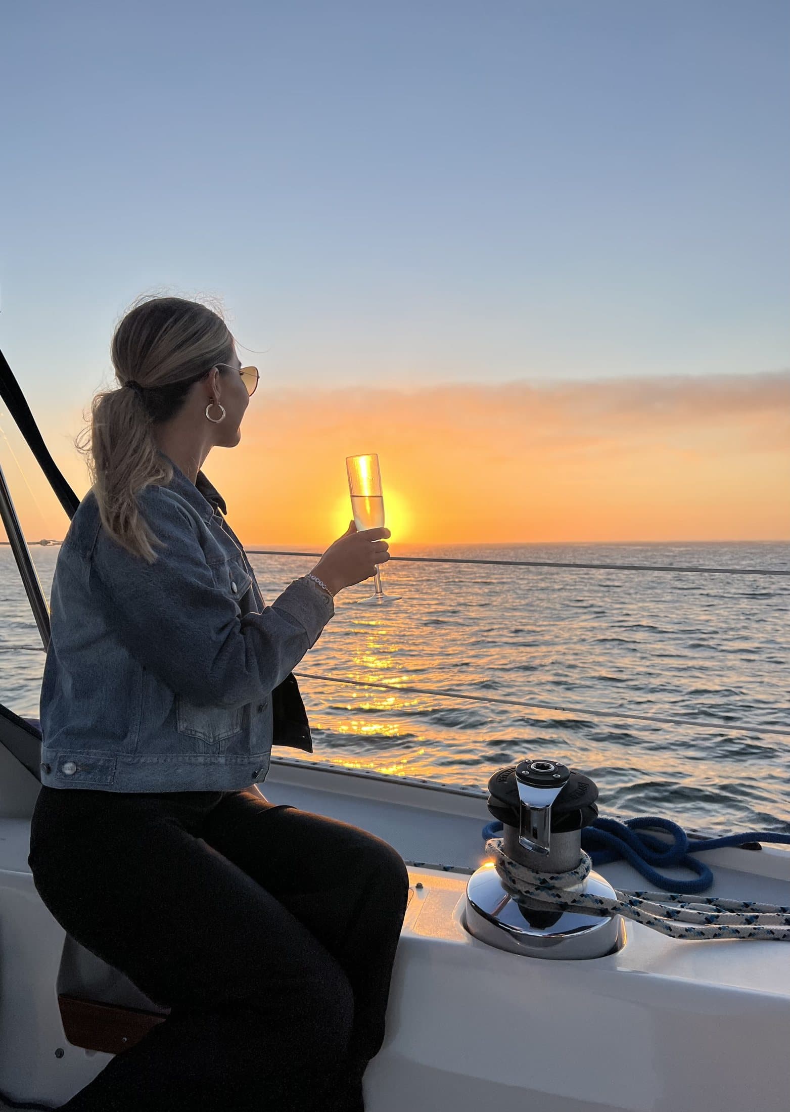 A guest raising champagne toward the sunset on a private San Diego sailing charter